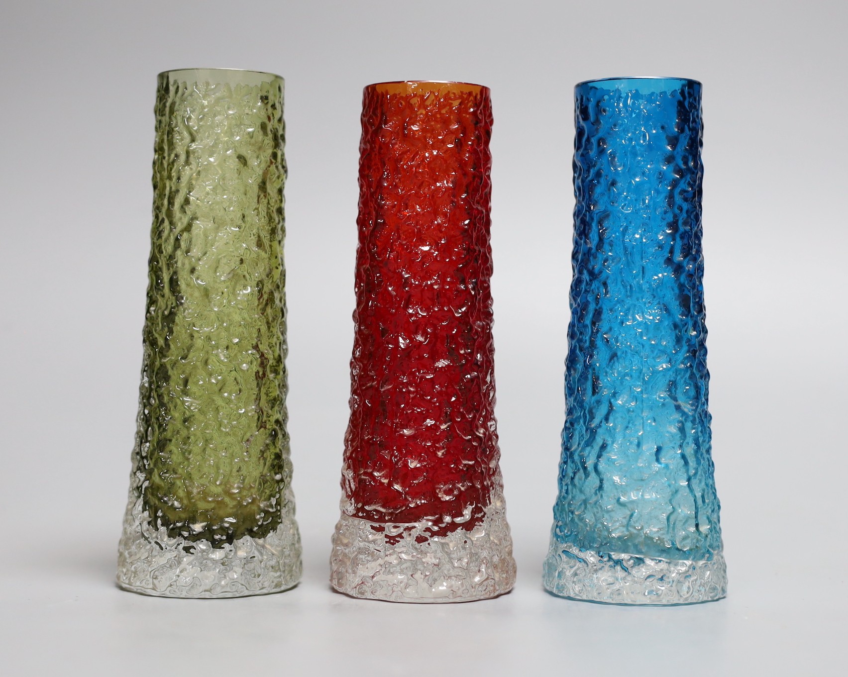 A trio of tapering 'bark' Whitefriar vases, model 9729 designed by Geoffrey Baxter, in red, kingfisher blue and sage green glass, each 16cm high.